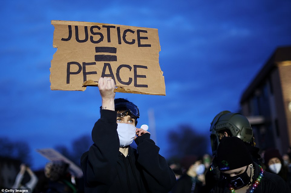 A demonstrator holds up a sign during a protest outside the Brooklyn Center police station on Saturday night