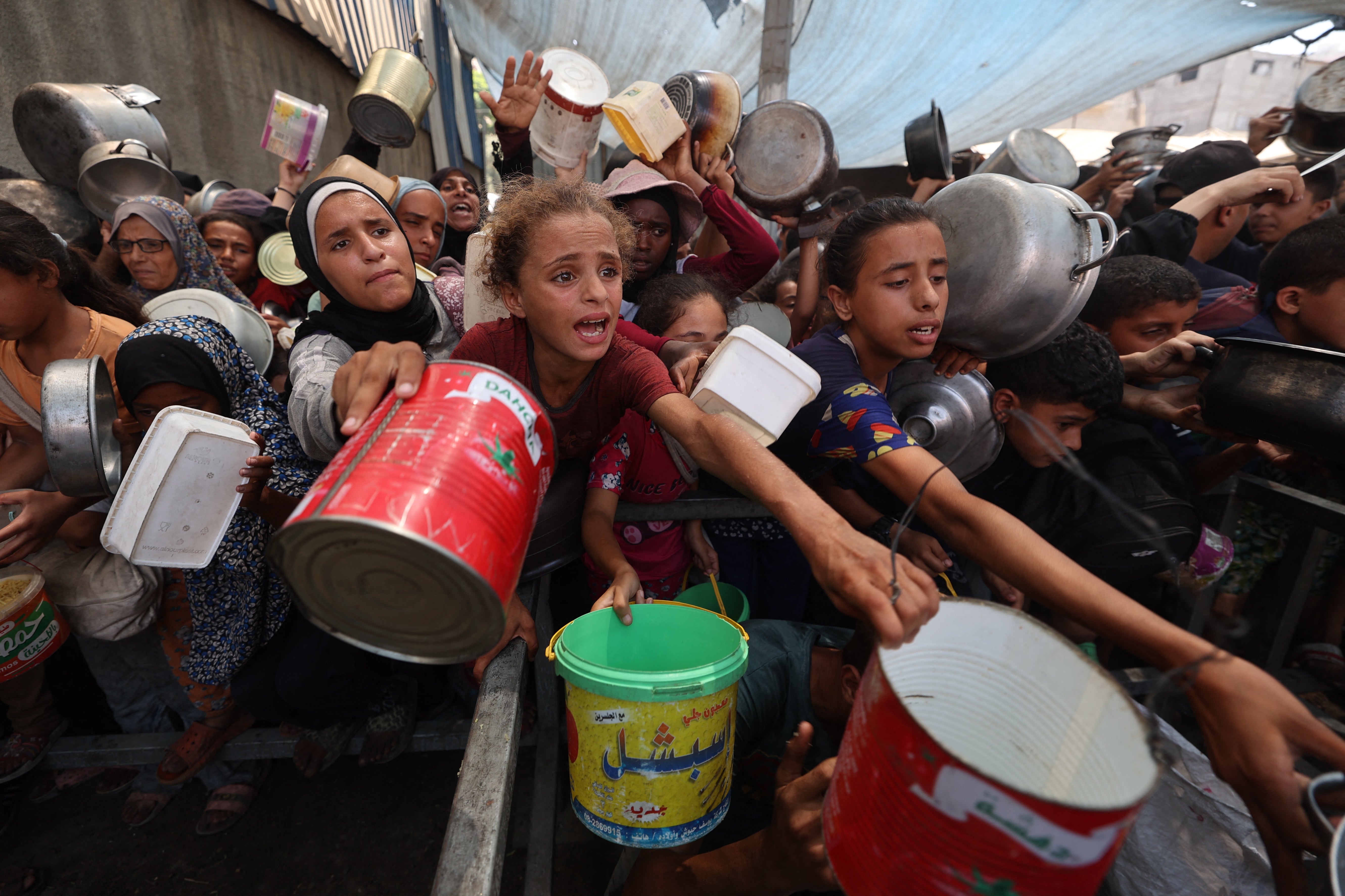 Palestinians gather to receive cooked meals from a food distribution centre in the Nuseirat refugee camp in the central Gaza Strip in August