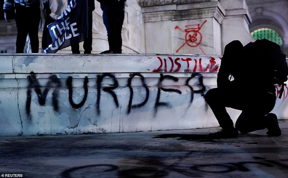 A demonstrator spray-paints at Union Station near the U.S Capitol, during a march in Washington, D.C. on Saturday