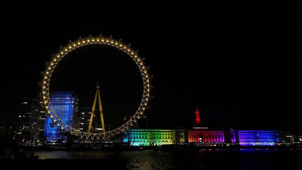Landmark and tourist attraction The London Eye is illuminated in yellow light as part of the National Day of Reflection on the anniversary of the first national Covid-19 lockdown, in central London on March 23, 2021.