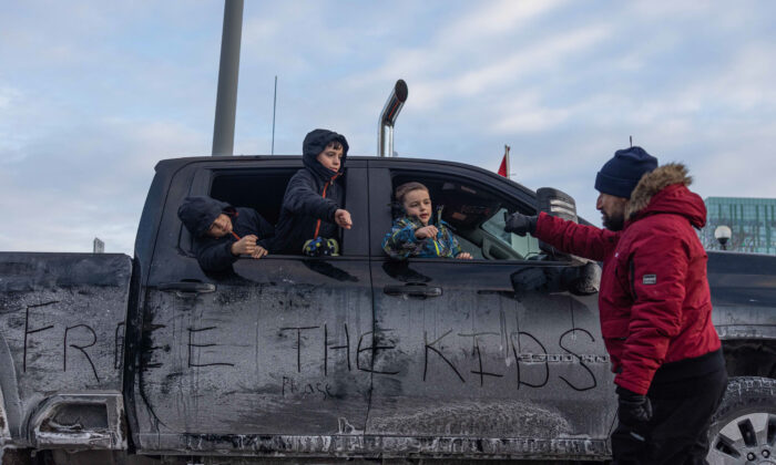 Children lean out of a vehicle to fist-pump a passing protester, in Ottawa on Jan. 30, 2022. (Alex Kent/Getty Images)